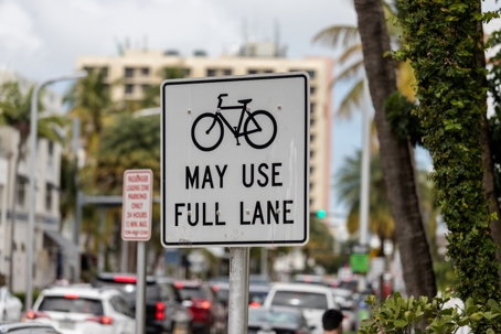 A traffic sign indicating bikes may use full lane with a picture of a bike in Miami Beach Florida.